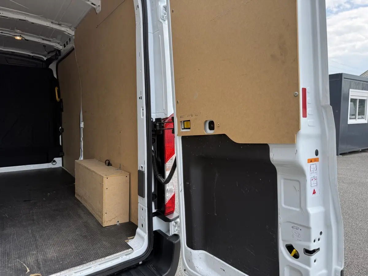 Vue intérieure arrière droite du fourgon blanc Ford Transit 2024, montrant la cloison et l'espace de chargement vide.