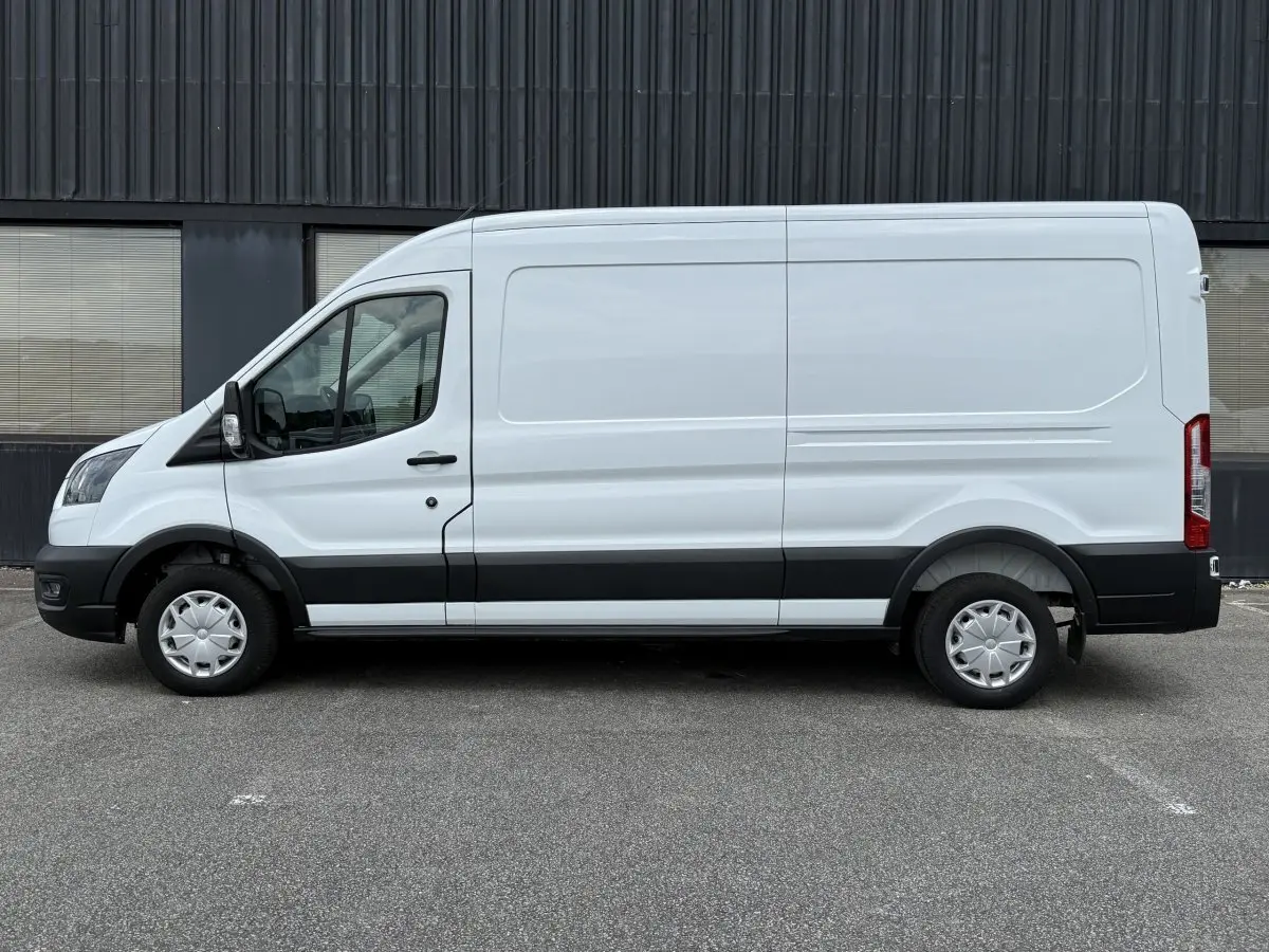 Vue de profil côté gauche d’un fourgon Ford Transit blanc avec bande noire et jantes acier.