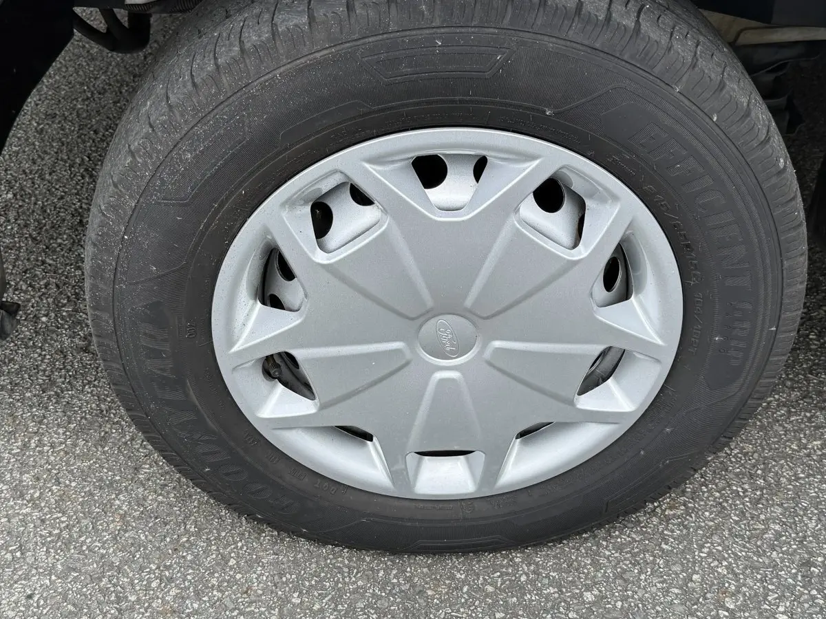 Gros plan sur la roue avant droite du Ford Transit Fourgon blanc, avec enjoliveur gris marqué du logo Ford.