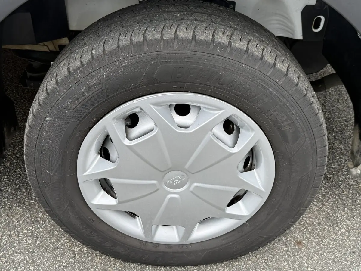 Gros plan sur la roue avant droite du Ford Transit Fourgon blanc, avec enjoliveur gris marqué du logo Ford.