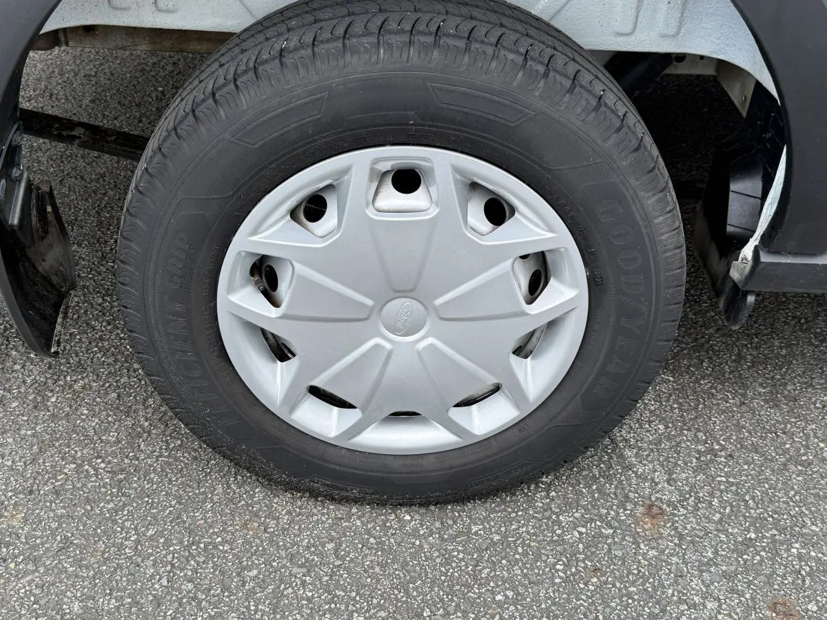Gros plan sur la roue avant droite du Ford Transit Fourgon blanc, avec jante en acier et enjoliveur gris.