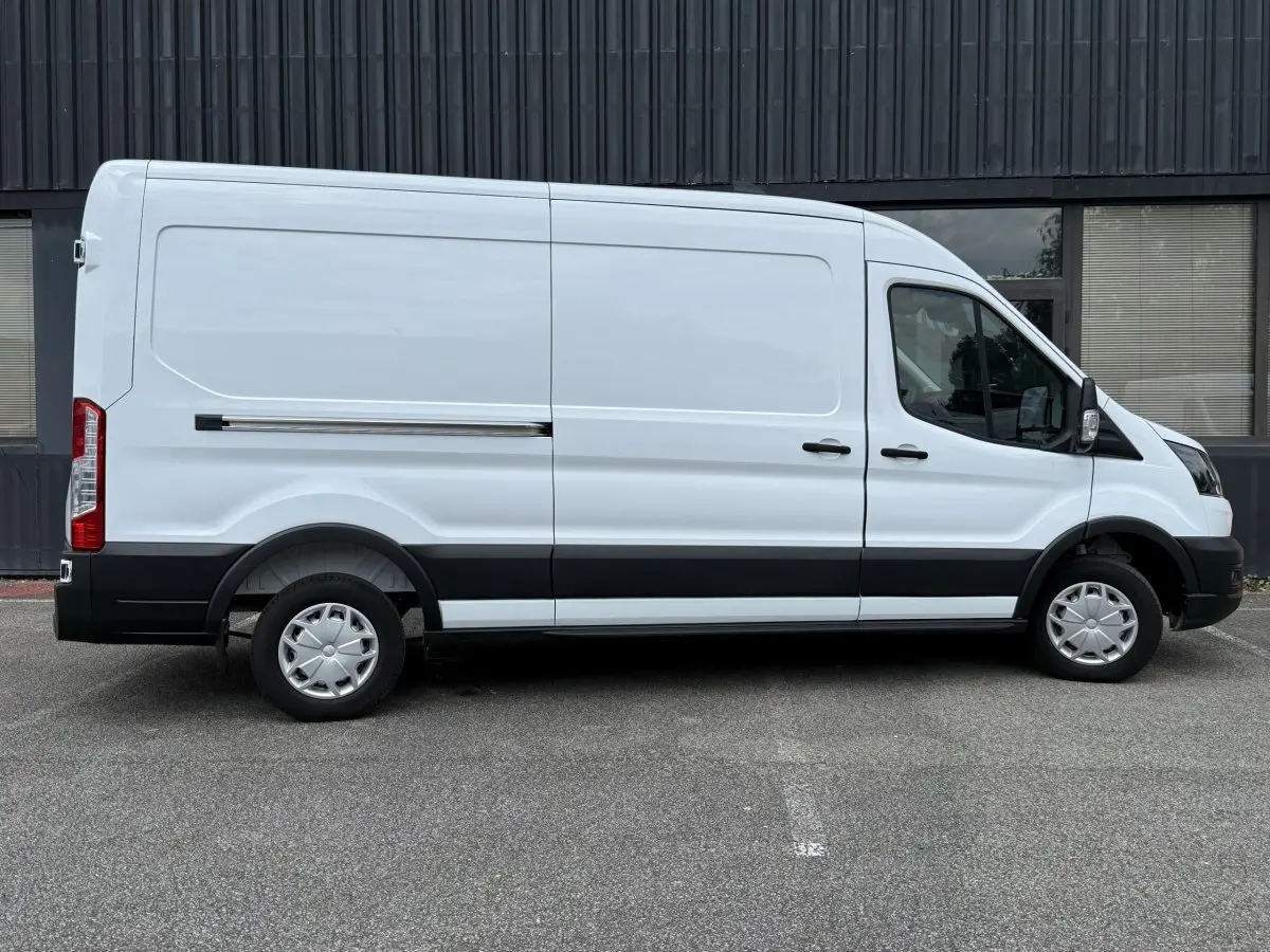 Vue latérale droite d’un fourgon Ford Transit blanc avec bande noire et jantes acier à enjoliveurs.