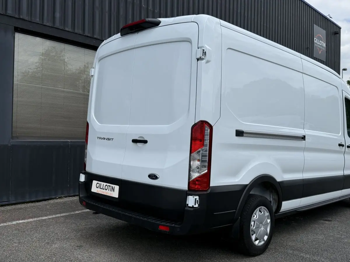 Vue 3/4 arrière droite d’un Ford Transit Fourgon blanc avec porte arrière pleine et pare-chocs noir.