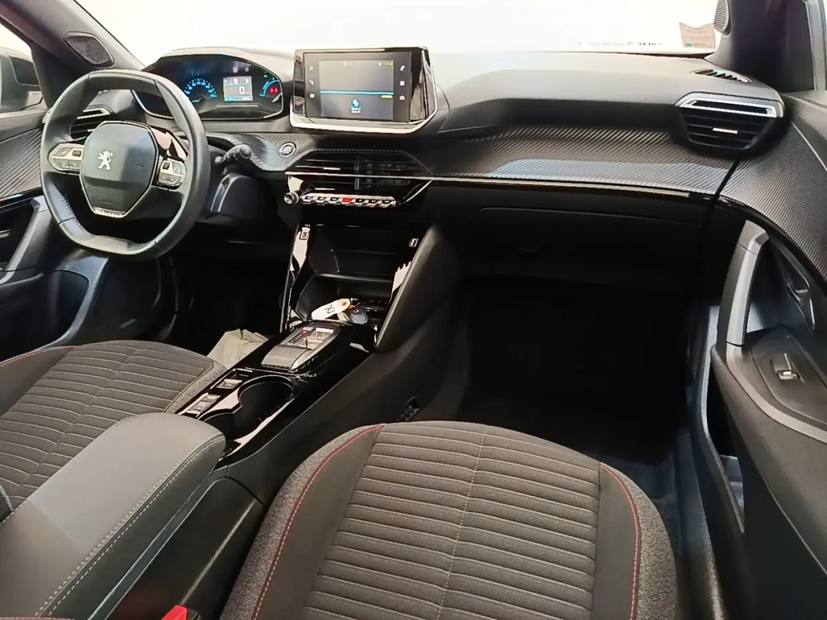 Intérieur du Peugeot E-2008 électrique gris clair, vue avant centrée sur le tableau de bord et le volant multifonctions cuir.