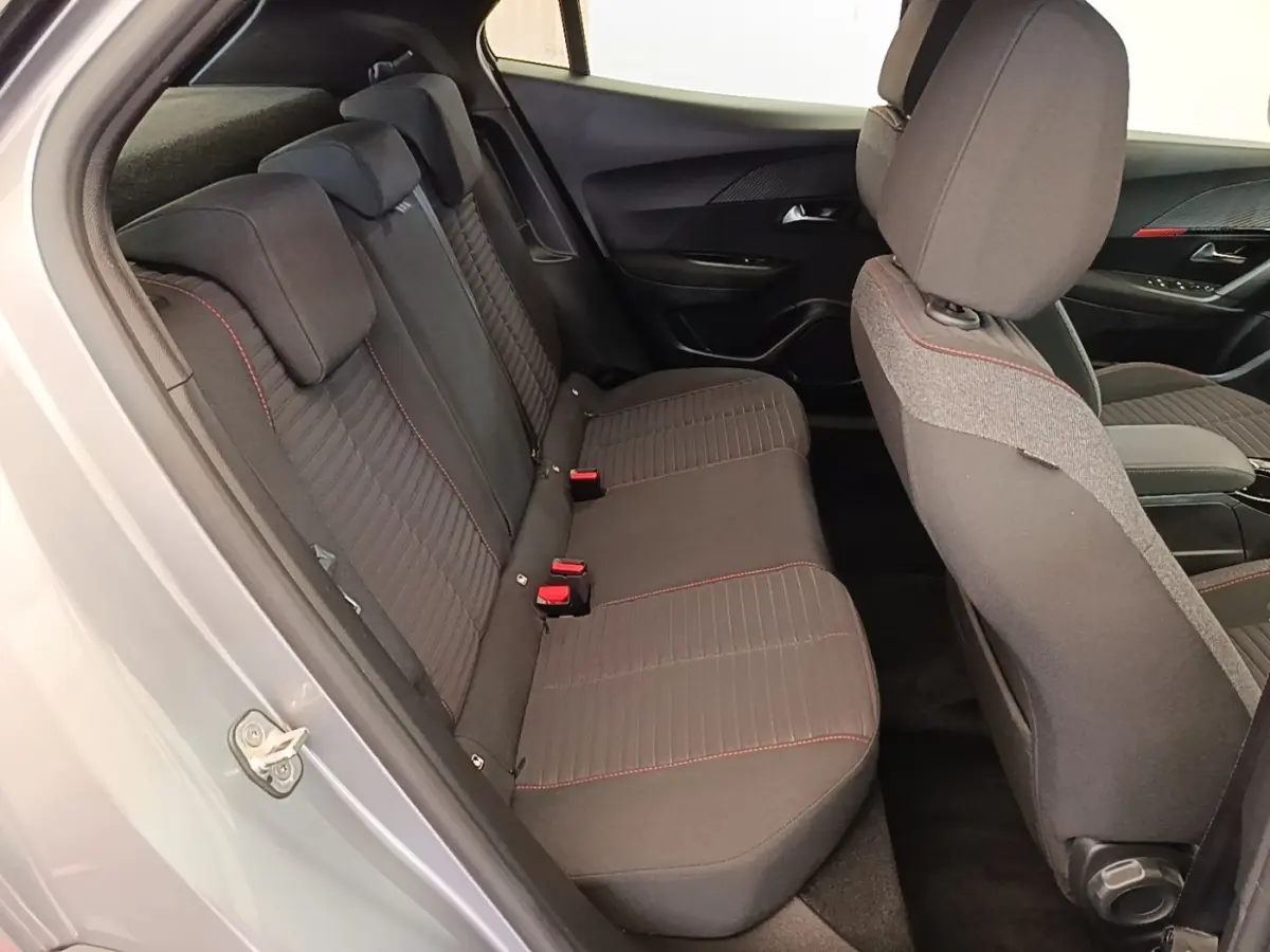 Vue intérieure côté gauche montrant la banquette arrière gris foncé avec surpiqûres rouges du Peugeot E-2008 électrique gris clair.