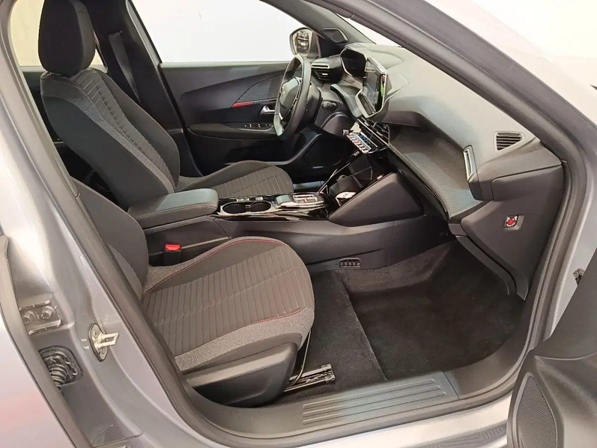 Vue intérieure côté passager avant du Peugeot E-2008 gris clair, avec sièges tissu et tableau de bord moderne.