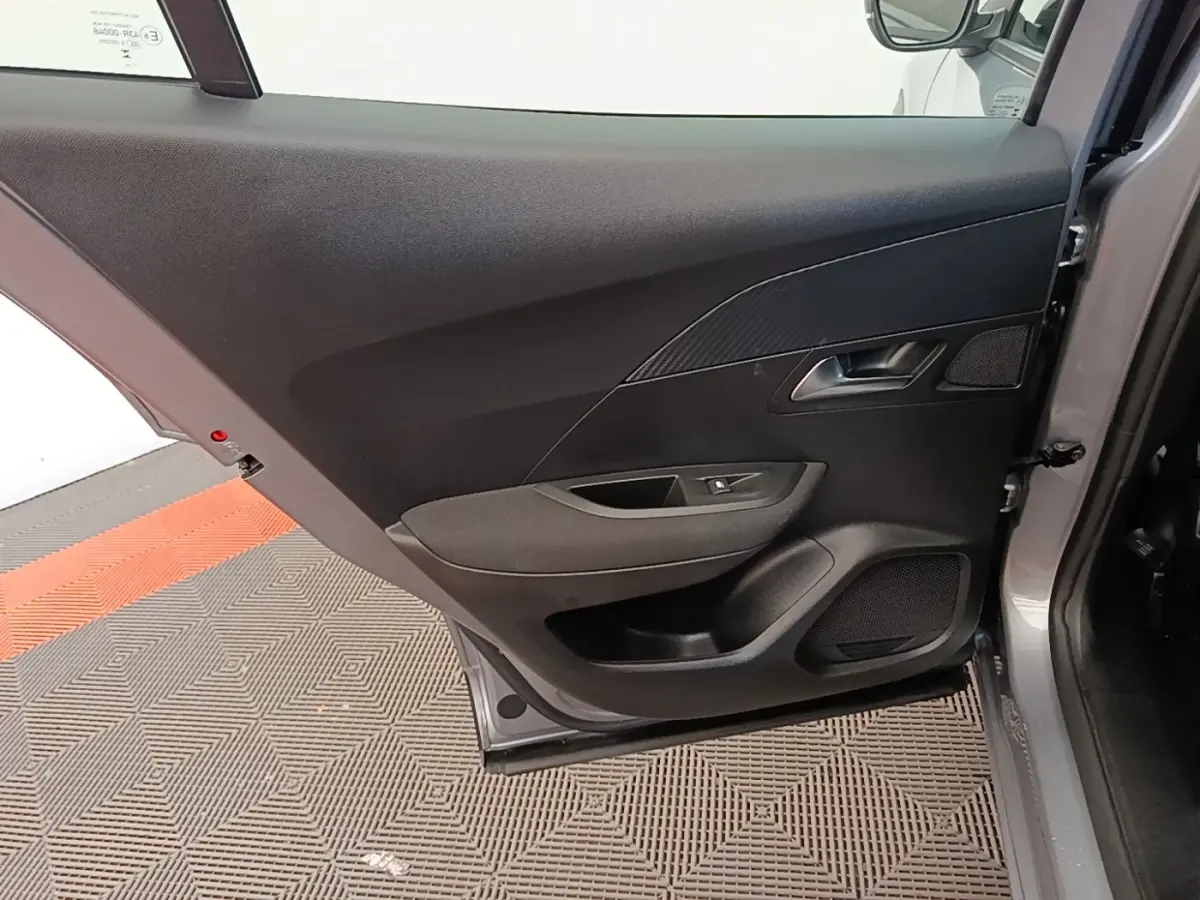 Vue intérieure de la porte arrière droite gris clair du Peugeot E-2008 électrique Active Pack 2023, avec poignée et haut-parleur intégrés.