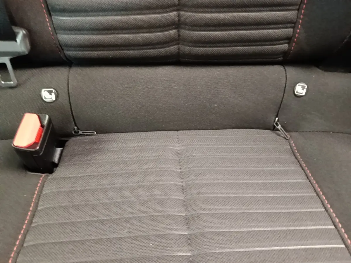 Gros plan sur la banquette arrière noire avec surpiqûres rouges et attaches Isofix du Peugeot E-2008 électrique.