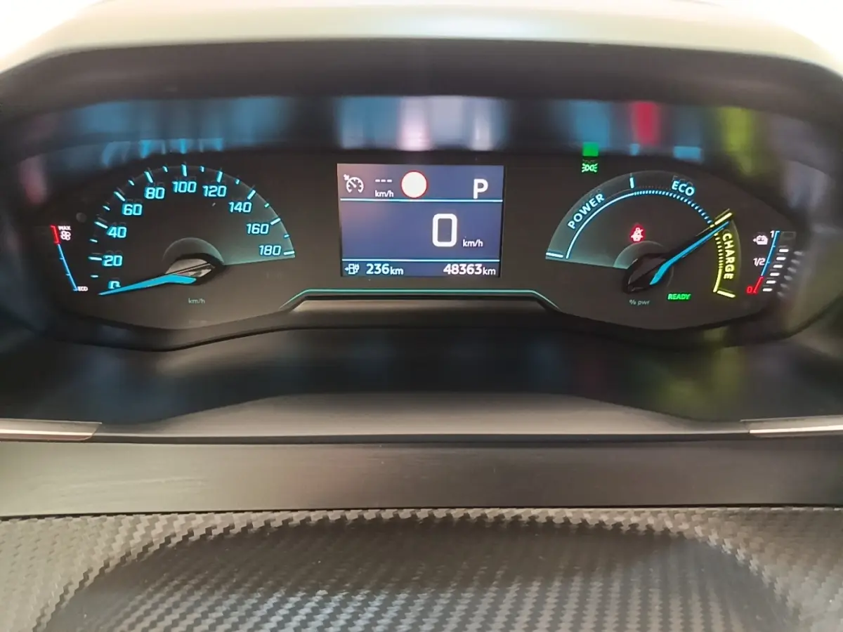 Tableau de bord numérique du Peugeot E-2008 électrique 2023, affichage vitesse, autonomie et mode éco en bleu et vert.