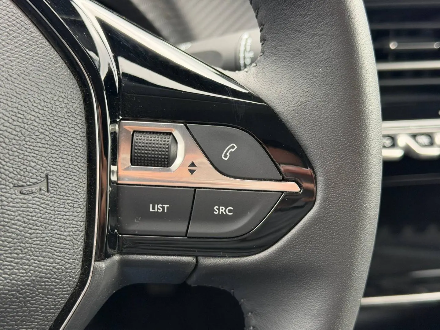 Gros plan sur les commandes noires du volant à droite du Peugeot 208 2025 Noir Perla Nera.