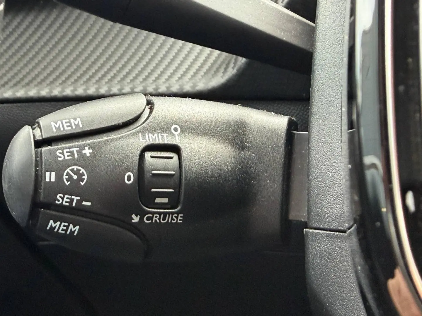 Gros plan sur la commande de régulateur de vitesse noire dans l’habitacle du Peugeot 208 noir Perla Nera.