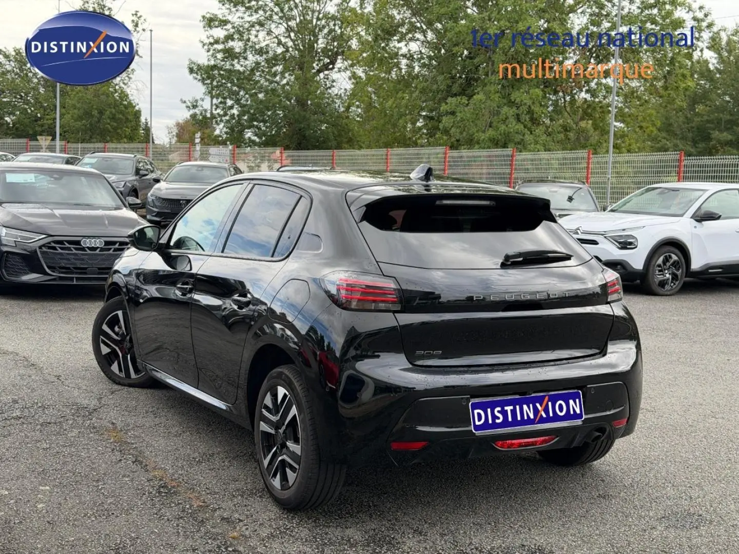 Vue 3/4 arrière droite d'une Peugeot 208 noire Perla Nera avec jantes alu, stationnée en extérieur.