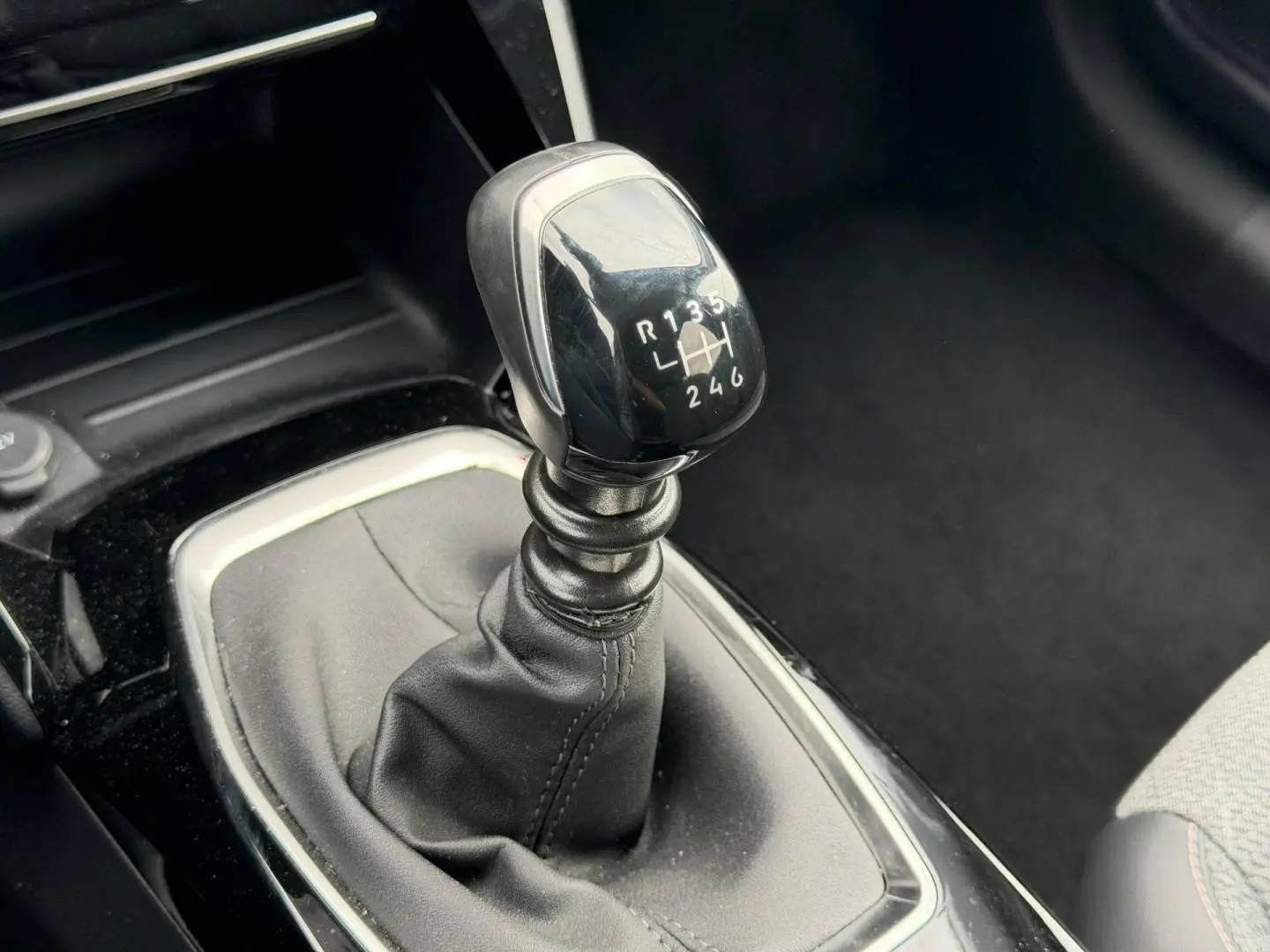 Gros plan sur le levier de vitesses manuel noir de la Peugeot 208 1.2 100ch Allure, intérieur tissu gris.