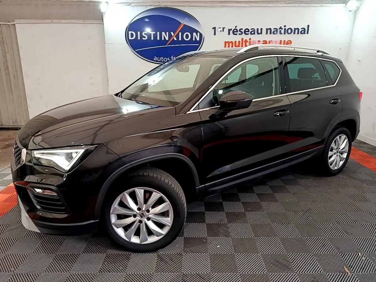 Vue 3/4 avant droite d'un SUV SEAT Ateca noir brillant, avec jantes alliage et barres de toit chromées en intérieur showroom.