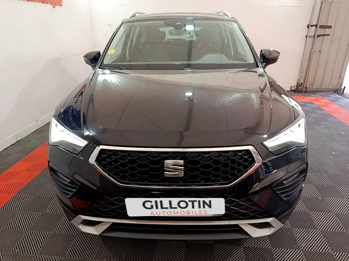 Vue frontale d'un SUV SEAT Ateca noir avec calandre hexagonale et phares LED allumés dans un garage.