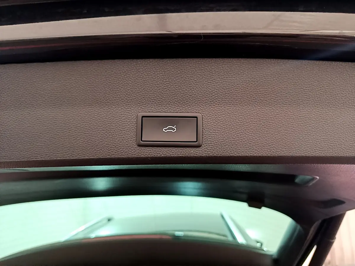 Bouton d'ouverture électrique du coffre sur la partie intérieure du hayon d'un SEAT Ateca noir, vue en contre-plongée.