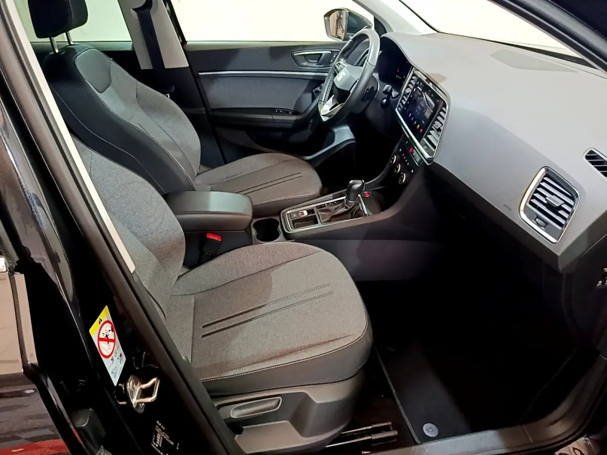 Intérieur avant droit d’un SEAT Ateca noir 2022, sièges gris, tableau de bord moderne avec écran tactile.