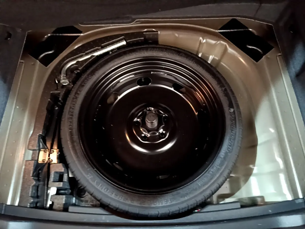 Roue galette de secours noire dans le coffre d'un SEAT Ateca 2022, vue plongeante sur le rangement sous tablette.