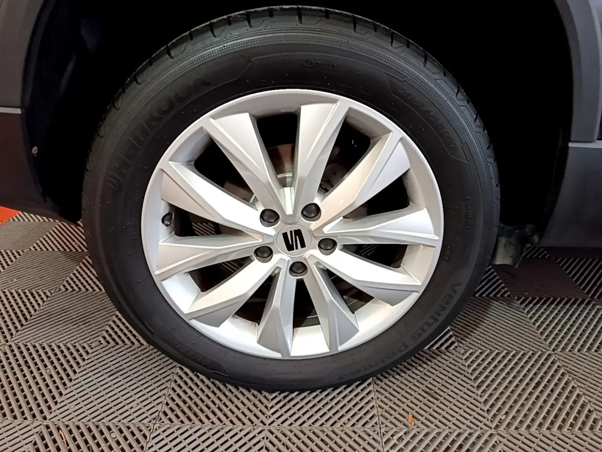 Gros plan sur la roue avant droite du SEAT Ateca noir, mettant en valeur la jante aluminium à dix branches.