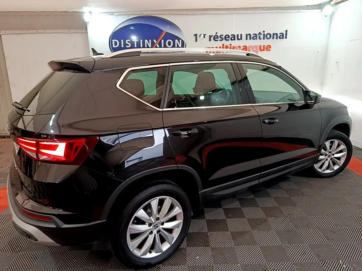 SEAT Ateca noir vue 3/4 arrière côté droit, feux arrière allumés et jantes alliage visibles en intérieur showroom