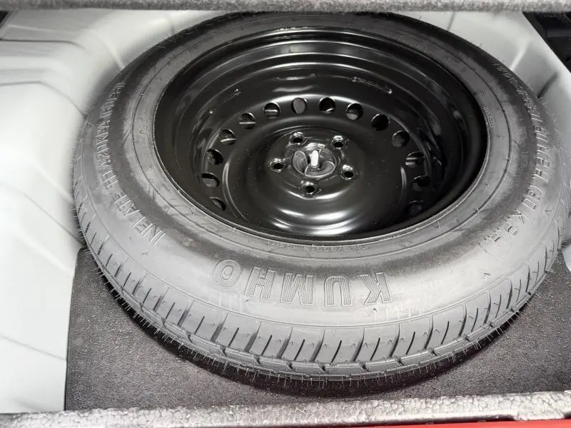 Gros plan sur la roue de secours noire dans le coffre du Renault Arkana blanc 2025, version hybride essence.