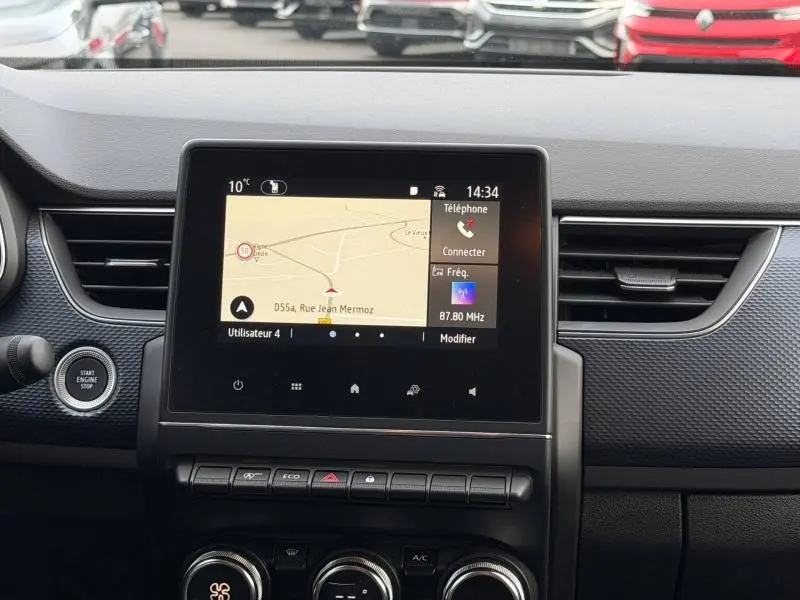 Vue intérieure centrée sur l'écran tactile du tableau de bord du Renault Arkana blanc avec navigation et commandes visibles.