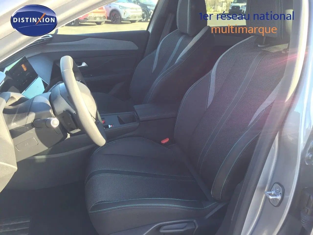 Vue intérieure côté conducteur de la Peugeot 308 gris Artense, montrant les sièges et le volant.