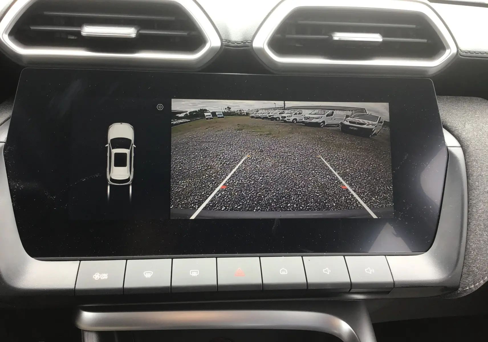 Écran tactile intérieur montrant la caméra de recul et l'affichage du véhicule en vue de dessus du MG ZS Cosmic Silver.