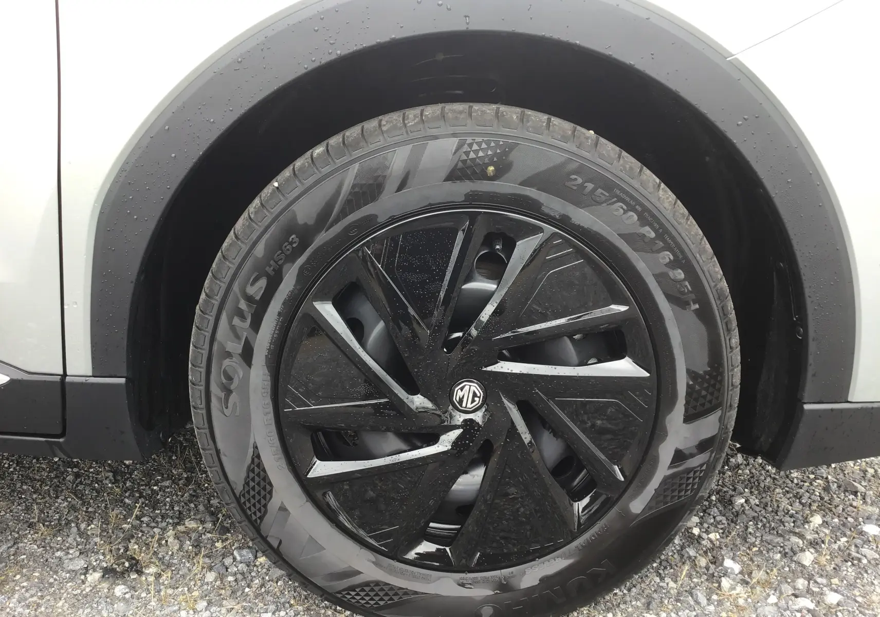 Gros plan sur la roue avant droite du MG ZS Cosmic Silver avec jante noire à motifs aérodynamiques.