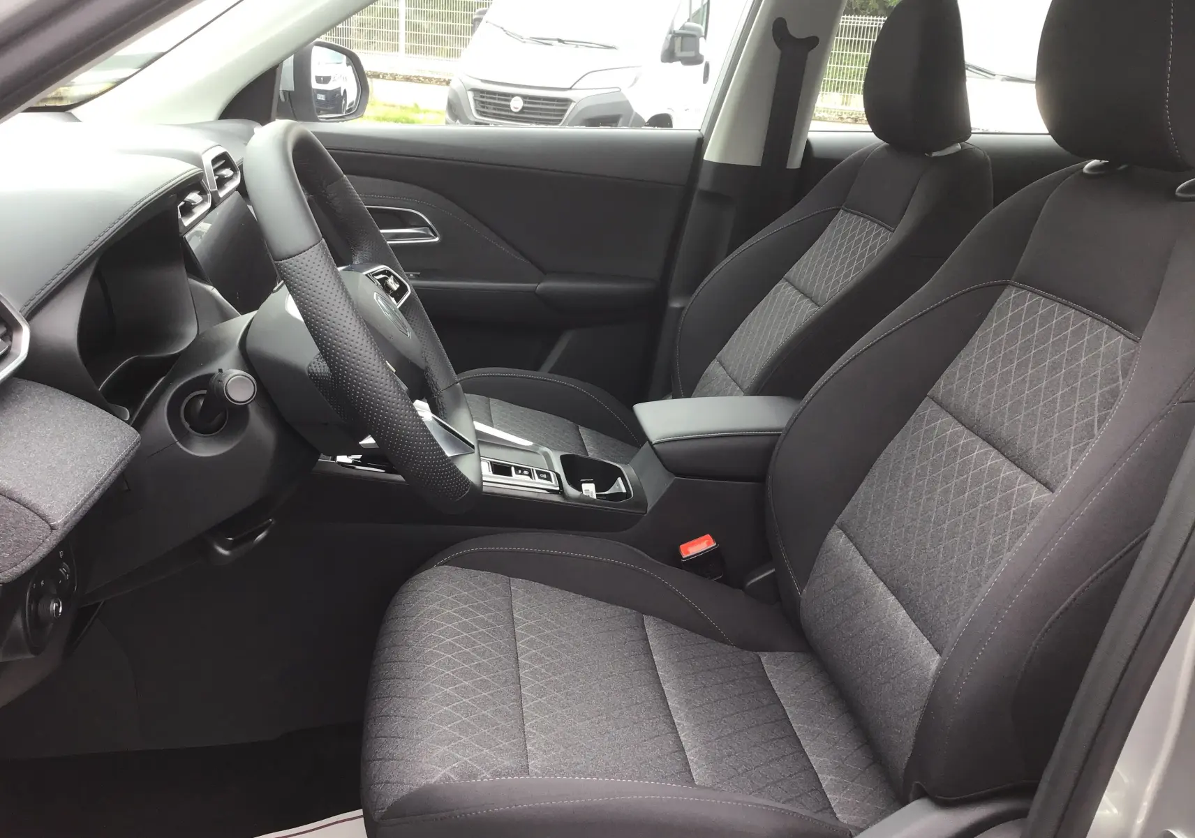 Vue intérieure côté conducteur du MG ZS Cosmic Silver 2026, sièges tissu noir avec console centrale et volant multifonction.