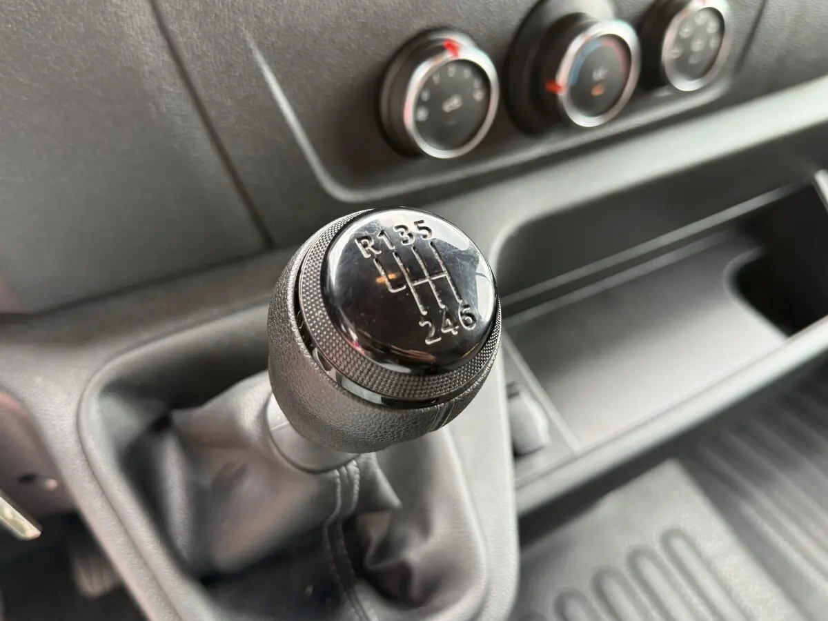Gros plan sur le levier de vitesses manuel noir du Renault Master 2024, avec commandes de climatisation en arrière-plan.