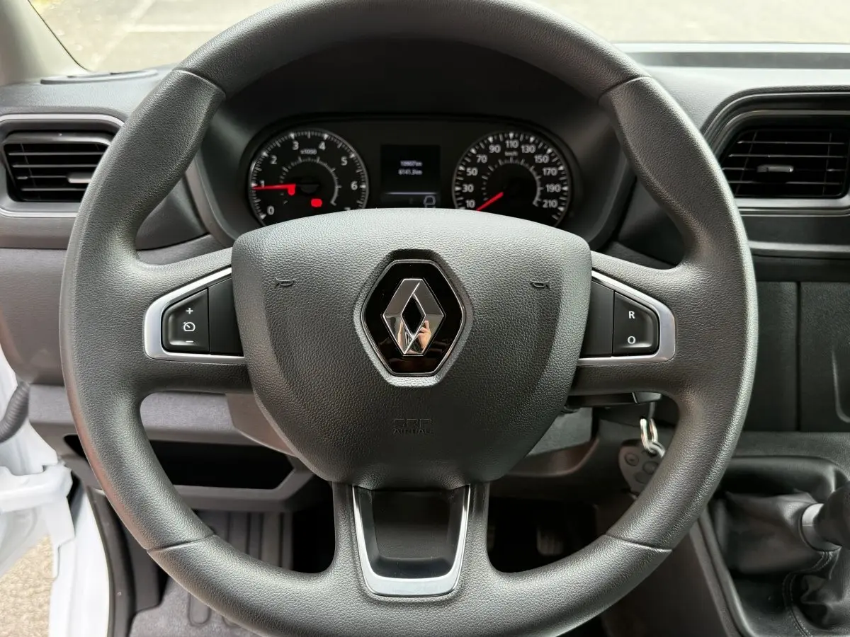 Vue rapprochée du volant noir du Renault Master 2024 avec logo central et tableau de bord en arrière-plan.