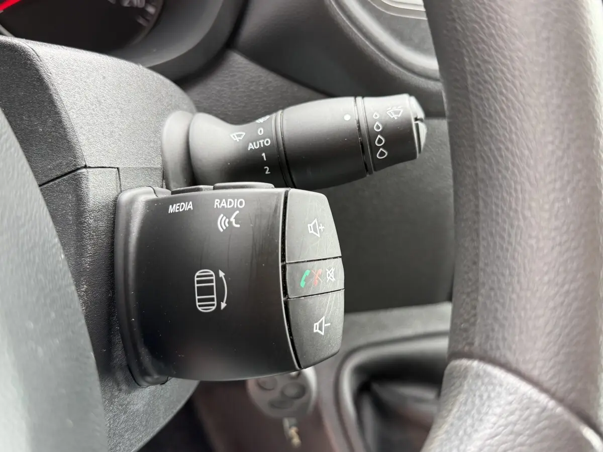 Gros plan sur commande multimédia et essuie-glace derrière volant noir du Renault Master 2024, intérieur sombre.
