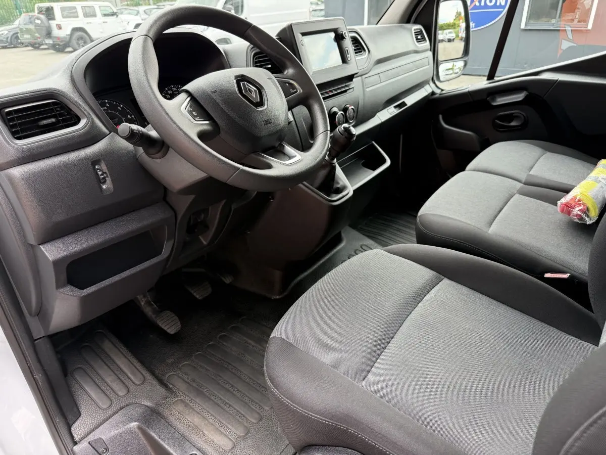 Intérieur du Renault Master 2024 vu côté conducteur, volant avec logo, sièges gris et tableau de bord avec écran tactile.