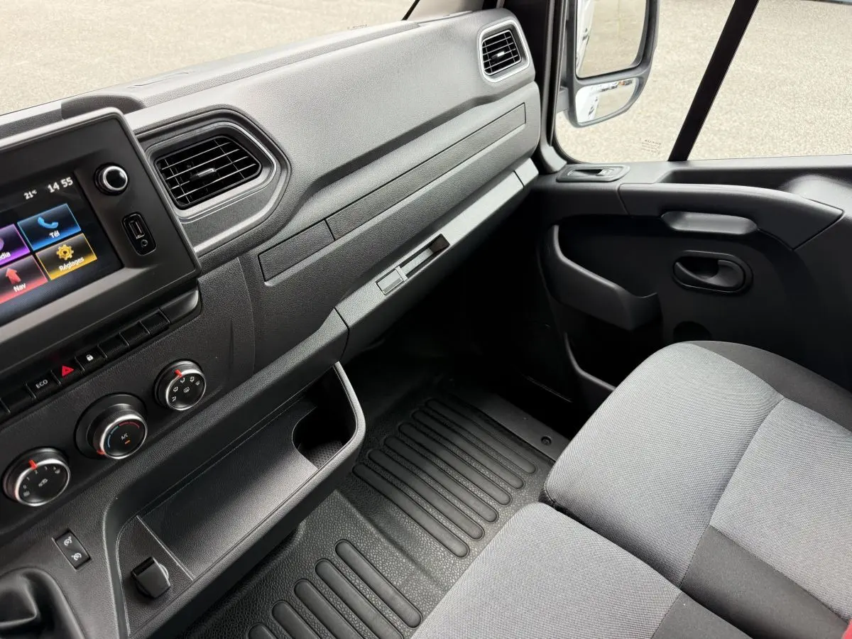 Vue intérieure côté passager du tableau de bord et siège gris du Renault Master 2024, avec écran tactile et commandes climatisation.