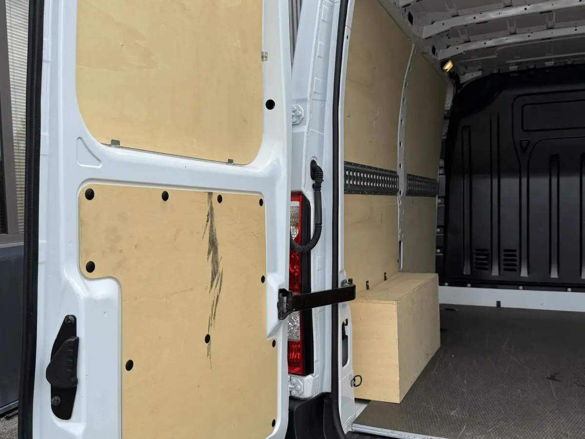 Vue intérieure arrière droite du Renault Master blanc 2024 avec cloison et aménagements en bois clair.