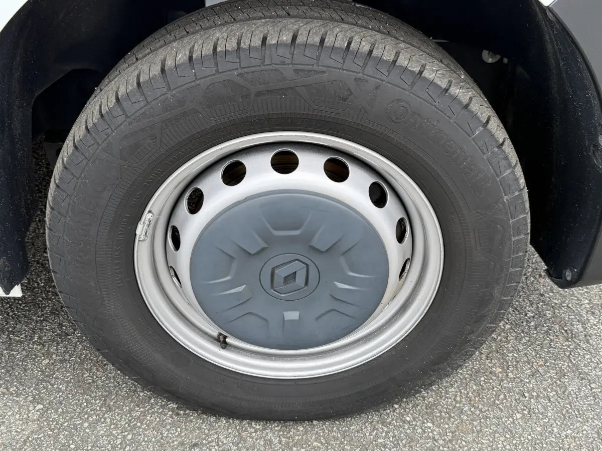 Gros plan sur la roue avant droite du Renault Master blanc, avec jante acier et logo Renault central gris.