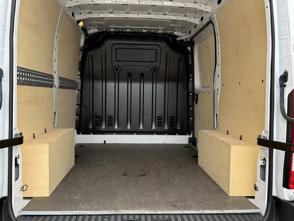 Vue intérieure arrière du Renault Master blanc 2024, montrant l'espace de chargement avec parois en bois et cloison noire.