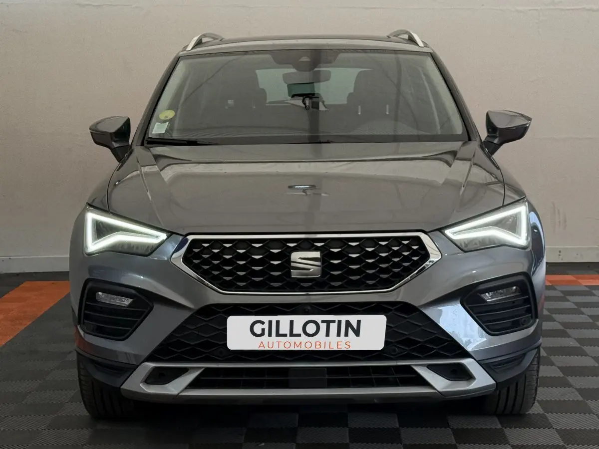 Vue frontale d'un SEAT Ateca gris clair 2023 avec phares LED allumés et calandre noire distinctive.