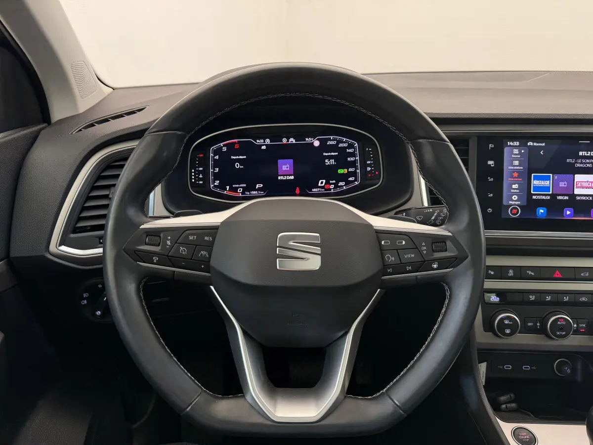 Vue intérieure centrée sur le volant cuir noir du SEAT Ateca 2023 avec tableau de bord digital et écran tactile.