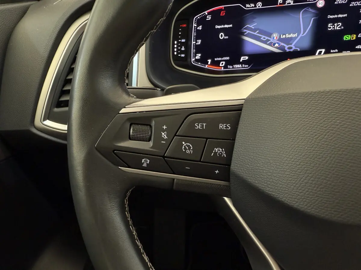 Gros plan sur le volant cuir noir du SEAT Ateca 2023 avec commandes de régulateur et tableau de bord numérique.