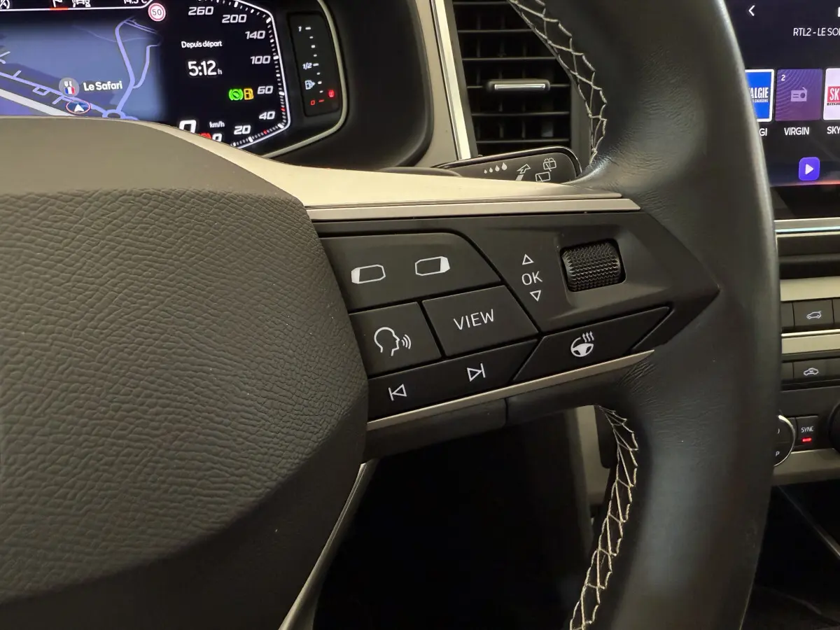 Gros plan sur les commandes du volant en cuir noir avec surpiqûres blanches du SEAT Ateca gris clair 2023.