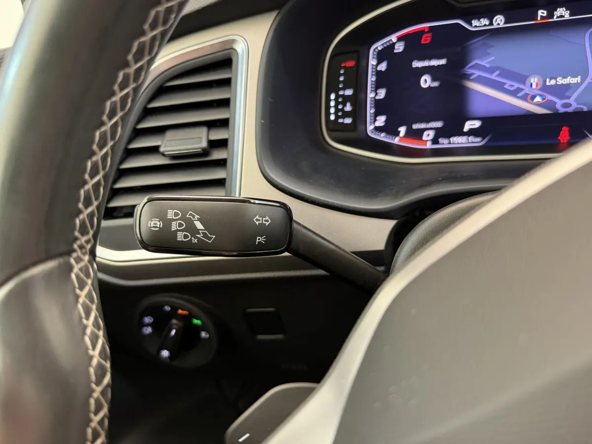 Gros plan sur le commodo gauche et le tableau de bord numérique bleu du SEAT Ateca gris clair 2023, vue côté conducteur.