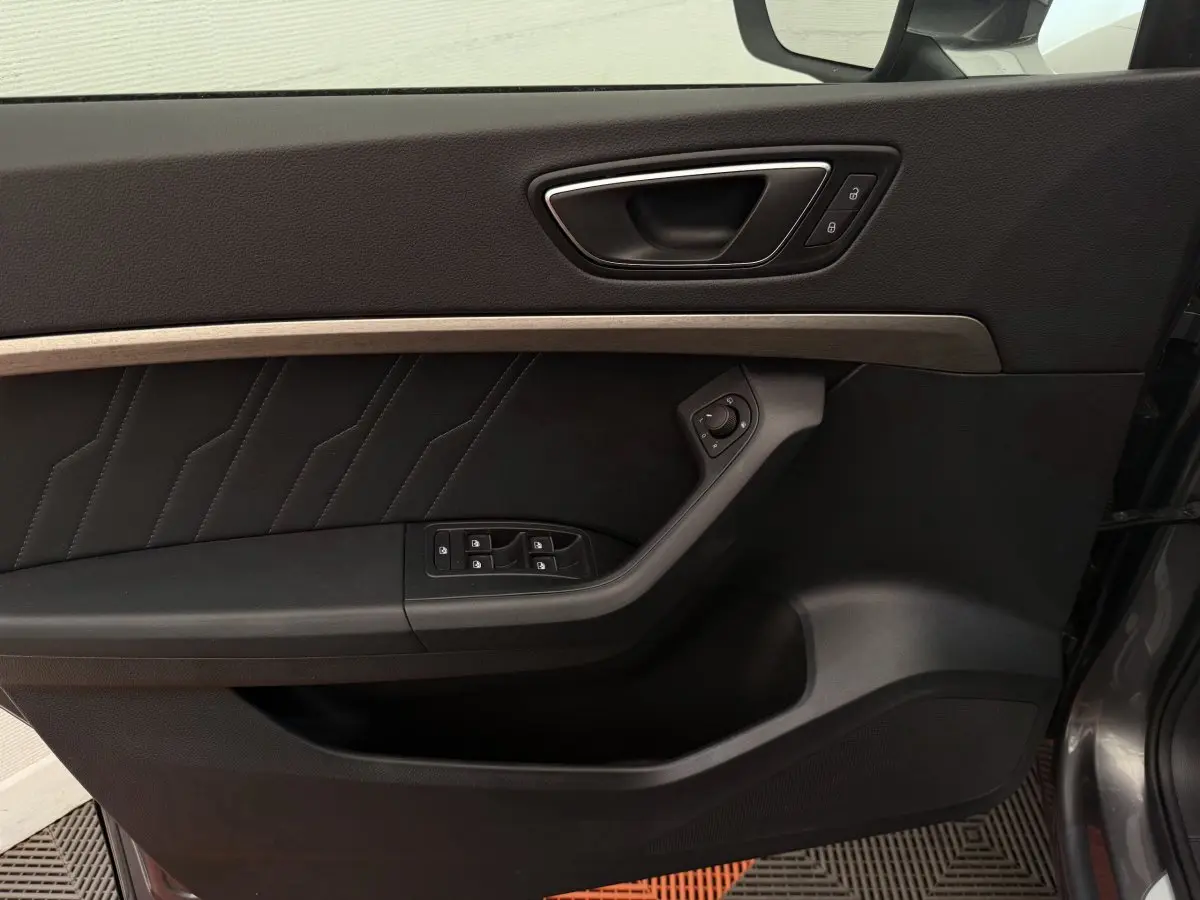 Porte intérieure côté gauche du SEAT Ateca gris clair, avec commandes électriques et insert décoratif bois.
