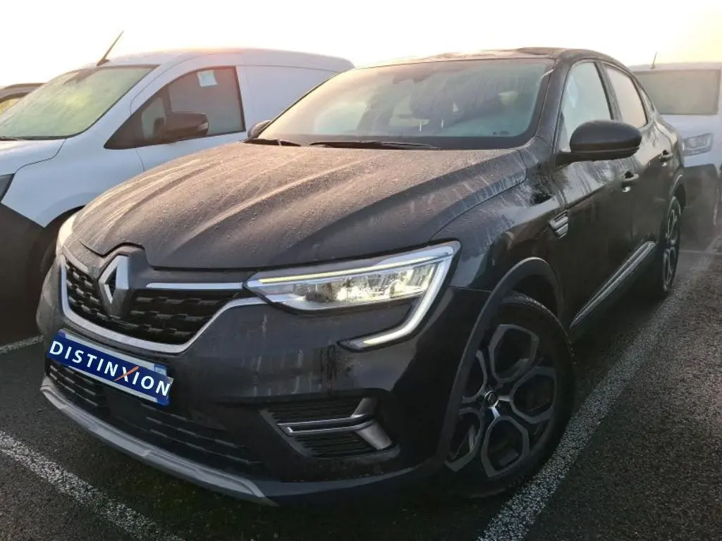 Vue 3/4 avant droit d’un Renault Arkana noir métal 2023 avec jantes bi-ton et calandre chromée, en intérieur showroom.