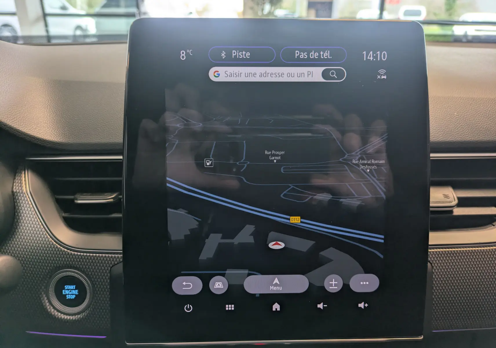 Vue rapprochée de l'écran tactile central noir affichant la navigation du Renault Arkana 2023, avec bouton Start Engine Stop à gauche.