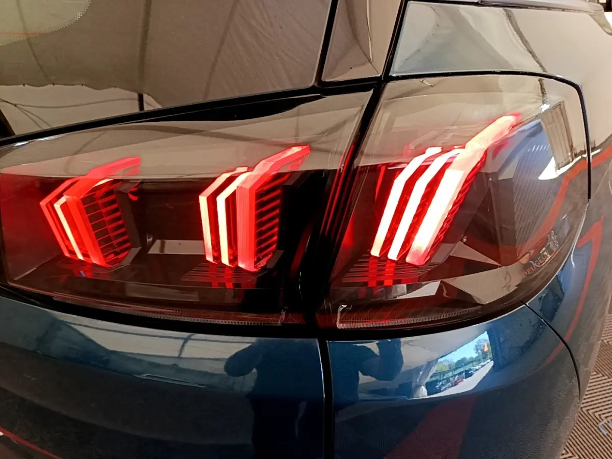 Gros plan sur les feux arrière allumés du Peugeot 5008 bleu, vue de l'angle arrière droit du véhicule.