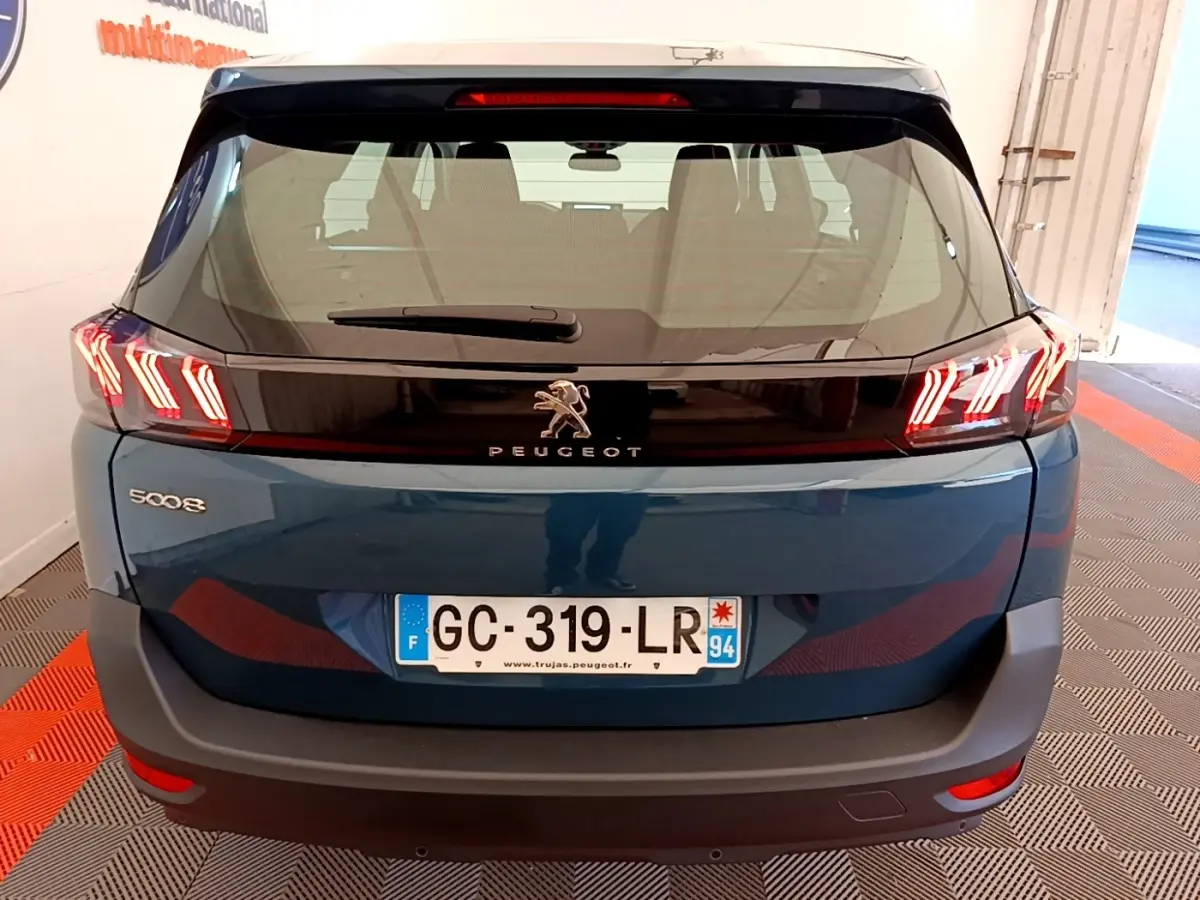 Vue arrière d’un Peugeot 5008 bleu 2021 avec feux LED caractéristiques et logo lion central sur hayon noir.
