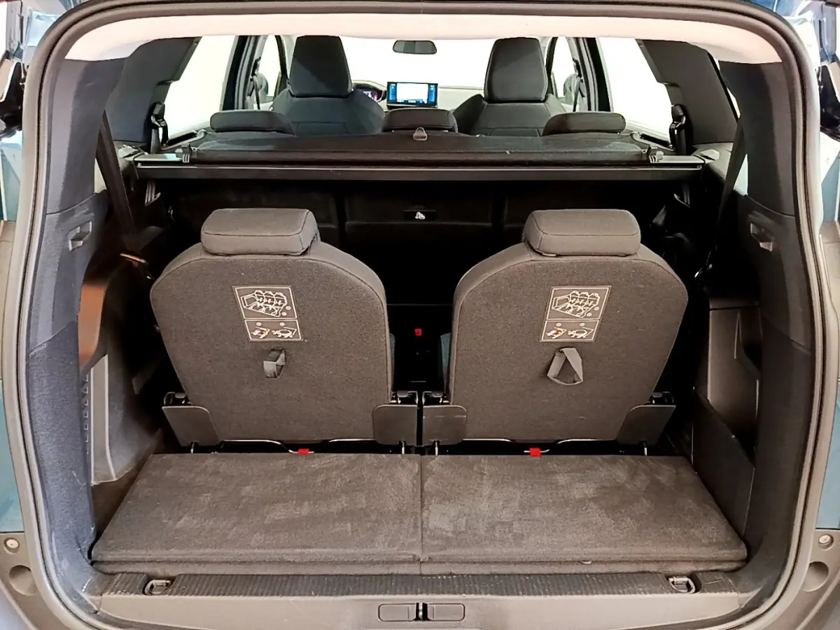 Vue arrière du coffre ouvert du Peugeot 5008 bleu, montrant la troisième rangée de sièges individuels relevés.