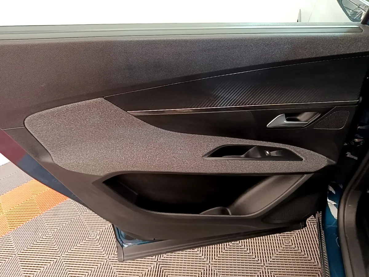 Vue rapprochée de la porte avant droite d’un Peugeot 5008 bleu, avec habillage tissu et insert imitation carbone.